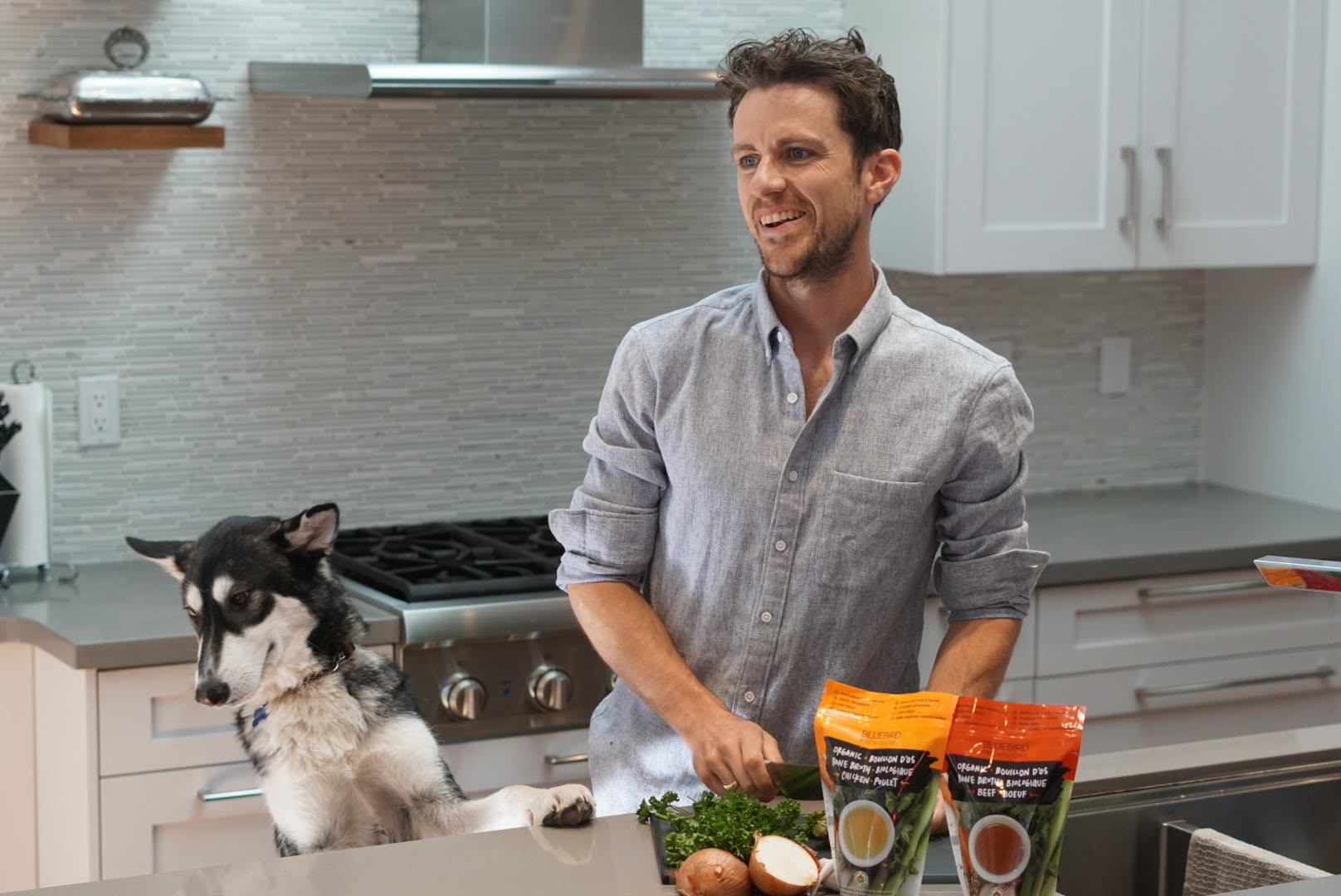 Connor from Bluebird Provisions organic bone broth chopping vegetables with his dog